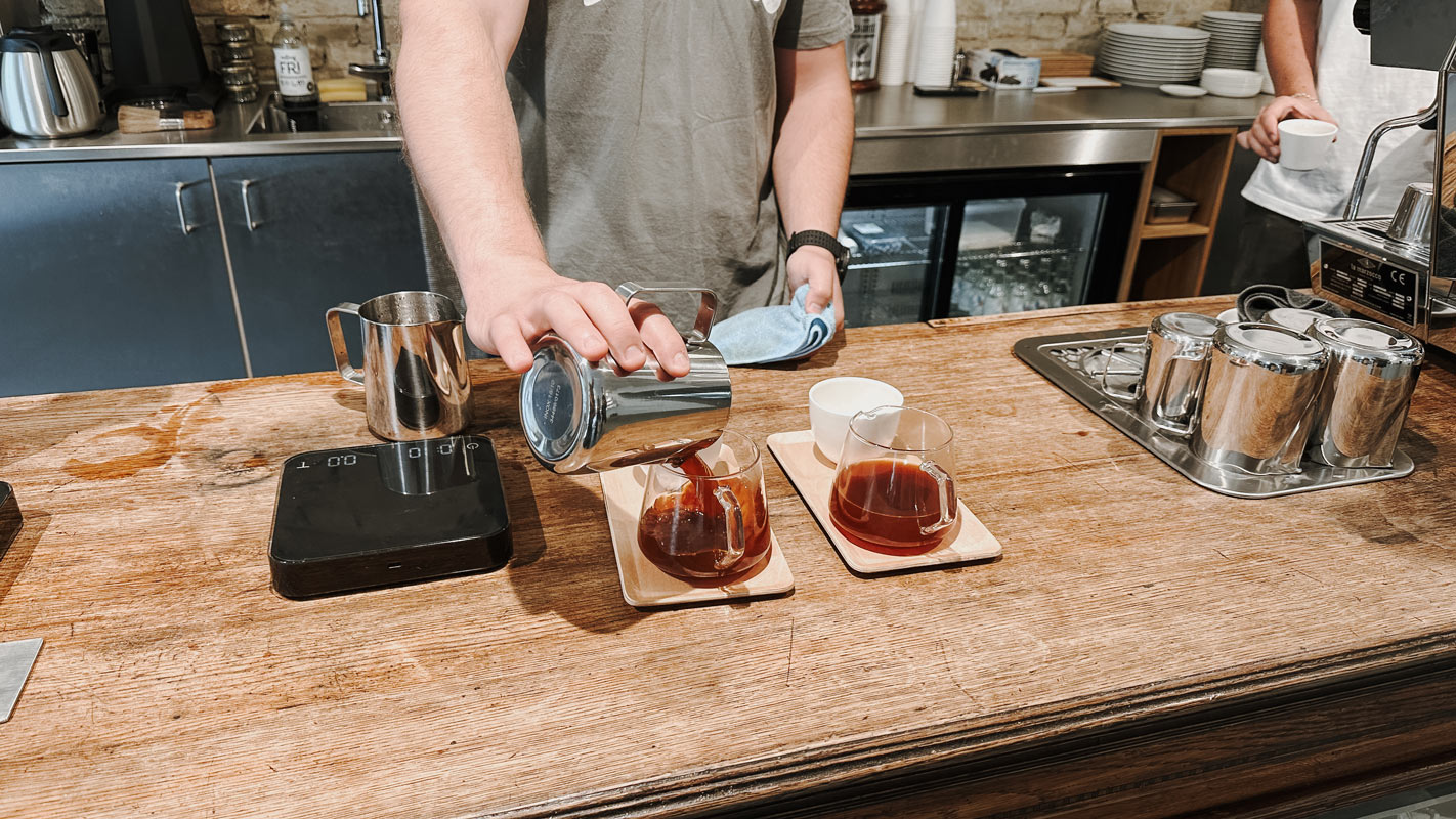 Barista schüttet Kaffee in Kanne