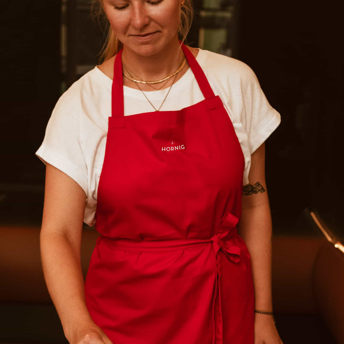 Eine junge Person mit einer roten J. Hornig Barista Schürze.