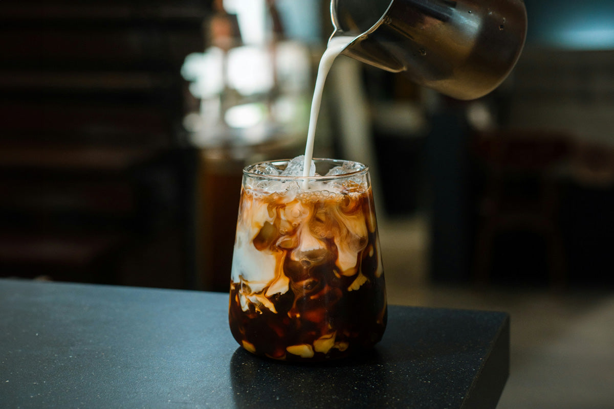 Ein Iced Latte Kaffee in einem Glas mit Eiswürfel.