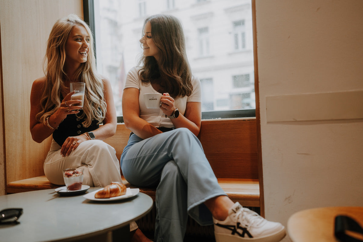 Zwei Freundinnen sitzen in der J. Hornig Kaffeebar und trinken Kaffee und unterhalten sich.